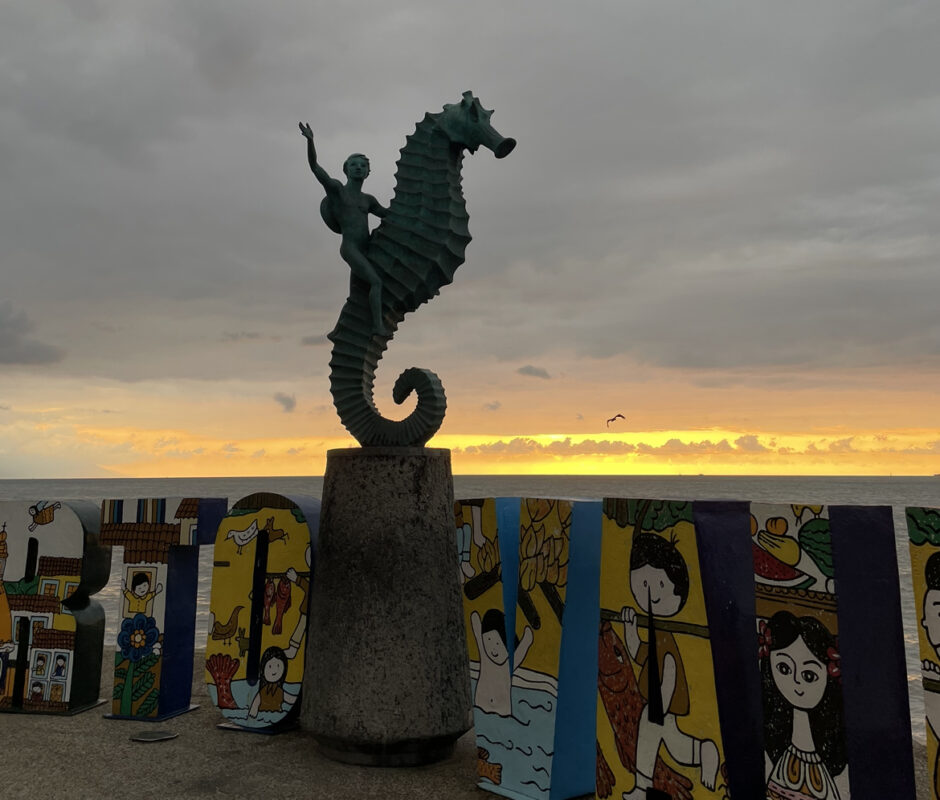 A statue of a boy on a seahorse during sunset. 