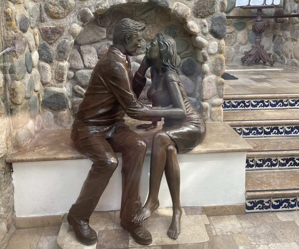 A bronze statue of a man and a woman sitting in a loving embrace.